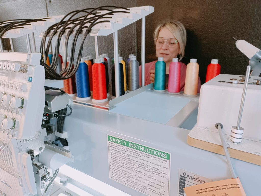 Brodeuse qui installe des bobines de fils sur la machine à broder
