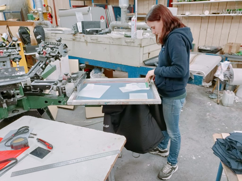 Sérigraphe qui applique de la peinture blanche sur un écran en toile